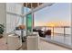 Dining room features a modern table set, floor-to-ceiling windows, and breathtaking water views at sunset at 1020 Sunset Point Rd # 703, Clearwater, FL 33755