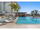 Beautiful pool area with clear blue water, comfortable lounge chairs, and shady palm trees, ideal for relaxation at 1020 Sunset Point Rd # 703, Clearwater, FL 33755