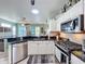 Modern kitchen with stainless steel appliances, white cabinets, and eat-in counter; open to the living room at 1219 Huntington Greens Dr, Sun City Center, FL 33573