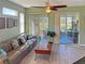 Relaxing living room features neutral green walls, sliding glass doors to a screened patio, and a comfortable gray couch at 1219 Huntington Greens Dr, Sun City Center, FL 33573