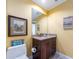 Bathroom with toilet, vanity, and decorative ocean-themed artwork, painted in light yellow at 1590 Gulf Blvd # 501, Clearwater Beach, FL 33767