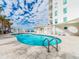 Beautiful pool with white building, palm trees, blue sky and white puffy clouds at 1590 Gulf Blvd # 501, Clearwater Beach, FL 33767