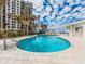 Beautiful pool with white building, palm trees, blue sky and puffy clouds at 1590 Gulf Blvd # 501, Clearwater Beach, FL 33767