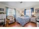 Cozy bedroom with natural light, wood floors, a floral chair, and a blue patterned bedspread at 1782 Coconut Dr, Venice, FL 34293