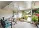 Screened porch features tile floors, comfortable seating, string lights and is surrounded by lush tropical landscaping at 1782 Coconut Dr, Venice, FL 34293
