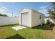 A spacious shed, featuring a roll up door and a small window, sits nestled within the property's well maintained grassy backyard at 1782 Coconut Dr, Venice, FL 34293
