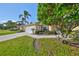 Inviting home exterior features a well-maintained lawn, palm trees, and a screened garage at 1912 Acadia Greens Dr, Sun City Center, FL 33573