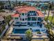 Aerial view of a luxurious multi-story home with a tile roof, pool, jacuzzi, and waterfront access at 199 21St Ave, St Pete Beach, FL 33706