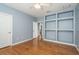 Blue bedroom featuring hardwood floors, built-in shelving, and an attached bathroom at 6615 Ridge Top Dr, New Port Richey, FL 34655