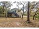 The exterior of the yellow home has a staircase, a deck, and is surrounded by mature trees at 6615 Ridge Top Dr, Trinity, FL 34655