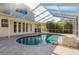Screen enclosed pool with a stone feature, brick paver deck, and a covered lanai at 6615 Ridge Top Dr, Trinity, FL 34655
