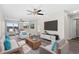 Bright living room with neutral tones, modern furnishings, ceiling fan, and large TV at 7086 Chatum Light Run, Bradenton, FL 34212