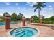 Community hot tub with tile steps surrounded by palm trees, lounge chairs, and red brick columns at 10263 Gandy N Blvd # 105, St Petersburg, FL 33702