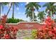 A close-up of the community sign surrounded by vibrant plants and palm trees against a bright blue sky at 10263 Gandy N Blvd # 105, St Petersburg, FL 33702