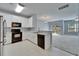 Well-equipped kitchen featuring white cabinetry, modern appliances, and seamless flow to the bright living room at 10621 Shady Falls Ct, Riverview, FL 33578