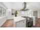 Bright kitchen featuring stainless steel appliances, white cabinetry, and a large center island with marble countertops at 1125 Fairwood Ave, Clearwater, FL 33759