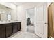 Double sink vanity in a neutral bathroom with dark cabinets, tile flooring, and access to the bedroom at 16126 Sunday Stroll Way, Odessa, FL 33556