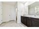 Bright bathroom featuring double sinks, a granite countertop, and dark brown cabinets at 16126 Sunday Stroll Way, Odessa, FL 33556