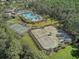 Aerial view of community tennis courts adjacent to a resort-style pool and surrounded by lush landscaping at 20115 Nob Oak Ave, Tampa, FL 33647