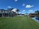 Expansive backyard featuring a screened lanai, lush lawn, white picket fence, and serene water view at 20115 Nob Oak Ave, Tampa, FL 33647