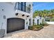 Close-up of the home featuring a brick driveway leading to a black garage door and a wrought iron balcony at 2113 S West Shore Blvd, Tampa, FL 33629