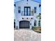 Close-up of the home featuring a brick driveway leading to a black garage door and a wrought iron balcony at 2113 S West Shore Blvd, Tampa, FL 33629
