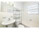 Bright white bathroom with a pedestal sink, tiled walls, and a shelving unit at 212 S Church Ave # 208, Tampa, FL 33609