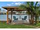 Relaxing waterfront covered dock featuring chairs, a small table, and lush green landscaping at 2146 Society Dr, Holiday, FL 34691