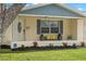 Charming front porch with a cozy bench with decorative pillows, enhanced by a lush lawn and well-maintained landscaping at 2146 Society Dr, Holiday, FL 34691