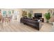 Open living room featuring a large brown leather sofa, light wood floors, and views of the exterior at 2146 Society Dr, Holiday, FL 34691