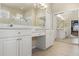 Elegant bathroom boasts dual vanities, white cabinets, tile flooring, and a view of the Primary bedroom at 2250 Long View Cir, Brooksville, FL 34604