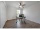 Neutral bedroom with wood-look floors, ceiling fan, and a desk by the window at 3025 Chessington Dr, Land O Lakes, FL 34638