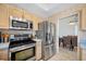 Cozy kitchen with stainless steel appliances, light wood cabinets and view into the dining area at 3042 Branch Dr, Clearwater, FL 33760