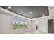 Bedroom with tray ceiling, wood-look floors, windows and a dark door to the en-suite bathroom at 3404 S Omar Ave, Tampa, FL 33629