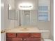 This bathroom features dark wood cabinetry, a large mirror, and a window for natural light at 3622 Wiregrass Rd, New Port Richey, FL 34655