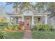 Charming home featuring a welcoming front porch, red door, and beautiful landscaping at 3622 Wiregrass Rd, New Port Richey, FL 34655