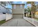 Rear view of home with an attached garage, gray door, and white picket fence at 3622 Wiregrass Rd, New Port Richey, FL 34655