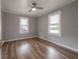 Bright bedroom features wood-look flooring, two windows, and a ceiling fan at 560 80Th N Ave, St Petersburg, FL 33702