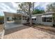 Charming home with a screened-in porch and carport, complemented by lush landscaping and a brick driveway at 560 80Th N Ave, St Petersburg, FL 33702