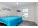 Comfortable bedroom with a plush blue bed, natural light from the window, and minimalist decor at 7015 N Dakota Ave, Tampa, FL 33604