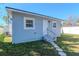 Exterior view of a charming home with light blue siding, decorative steps and a well-manicured lawn at 7015 N Dakota Ave, Tampa, FL 33604