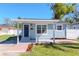 Charming single-story home featuring a cozy covered porch, brick walkway, and well-maintained lawn at 7015 N Dakota Ave, Tampa, FL 33604