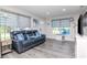 Inviting living room features stylish gray flooring, large windows, and a comfortable blue leather couch at 7015 N Dakota Ave, Tampa, FL 33604