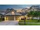 Charming single-Gathering home featuring a well-manicured lawn and a two-car garage against a picturesque evening sky at 12906 Tar Flower Dr, Tampa, FL 33626