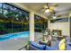 Inviting screened-in patio with a pool, ceiling fans, comfortable seating, and a grill for outdoor entertaining at 12906 Tar Flower Dr, Tampa, FL 33626