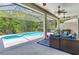 Relaxing screened-in patio features a pool, ceiling fans, comfortable seating, and a built-in grill for outdoor entertaining at 12906 Tar Flower Dr, Tampa, FL 33626