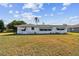 View of the home's rear exterior with a spacious lawn and minimal landscaping at 1730 Sunset Point Rd, Clearwater, FL 33755