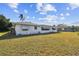 Lawn view of home's exterior with mature landscaping and shade awning at 1730 Sunset Point Rd, Clearwater, FL 33755