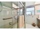 Bathroom featuring a walk-in shower with clear glass door and handle, and green tiling at 1730 Sunset Point Rd, Clearwater, FL 33755