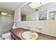 Bathroom featuring a large mirror over the sink and a glass-enclosed shower, with beige tile and decor at 1730 Sunset Point Rd, Clearwater, FL 33755